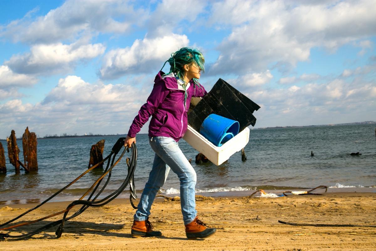 A volunteer drags debris off the beach at Jamaica Bay